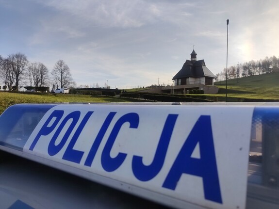 napis policja, kaplica cmentarna, na cmentarzu w Ustrzykach Dolnych, w tle